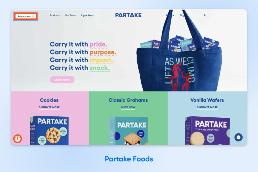 Captura de pantalla del sitio web de Partake Foods que muestra un destacado enlace de accesibilidad “Saltar al menú” en la esquina superior izquierda, con secciones de productos coloridas y una imagen de marca inclusiva