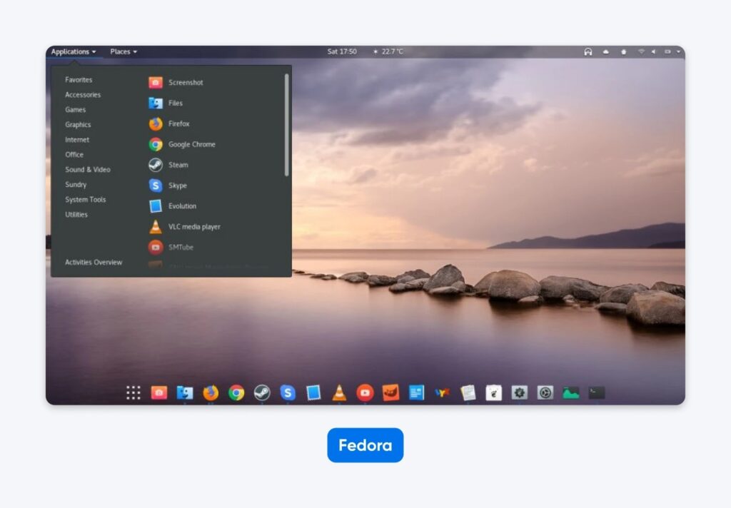 Fedora desktop interface with application menu open, dock icons visible, and a serene lake landscape as the wallpaper.
