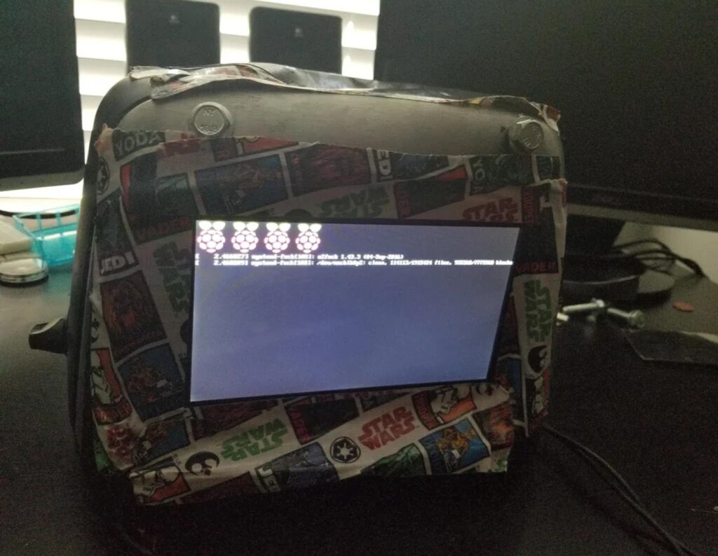 Small Raspberry Pi setup with a screen displaying boot text, enclosed in a case covered with Star Wars-themed tape.