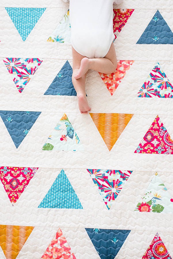Baby crawling on quilt with flower triangle pattern.