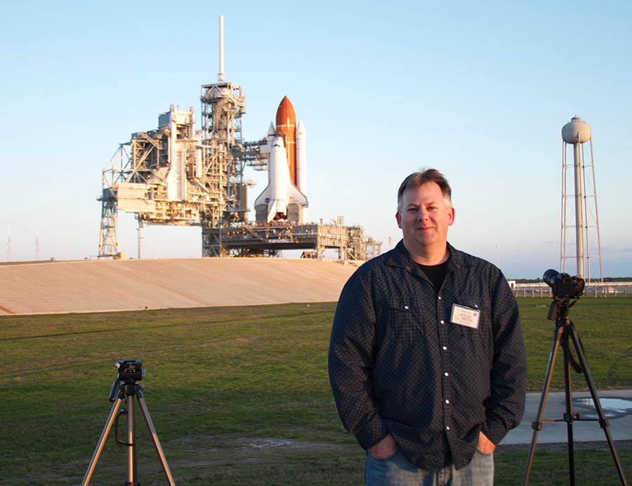 Chase Clark posando con el transbordador espacial Endeavour situado en la histórica plataforma de lanzamiento 39A en el fondo.