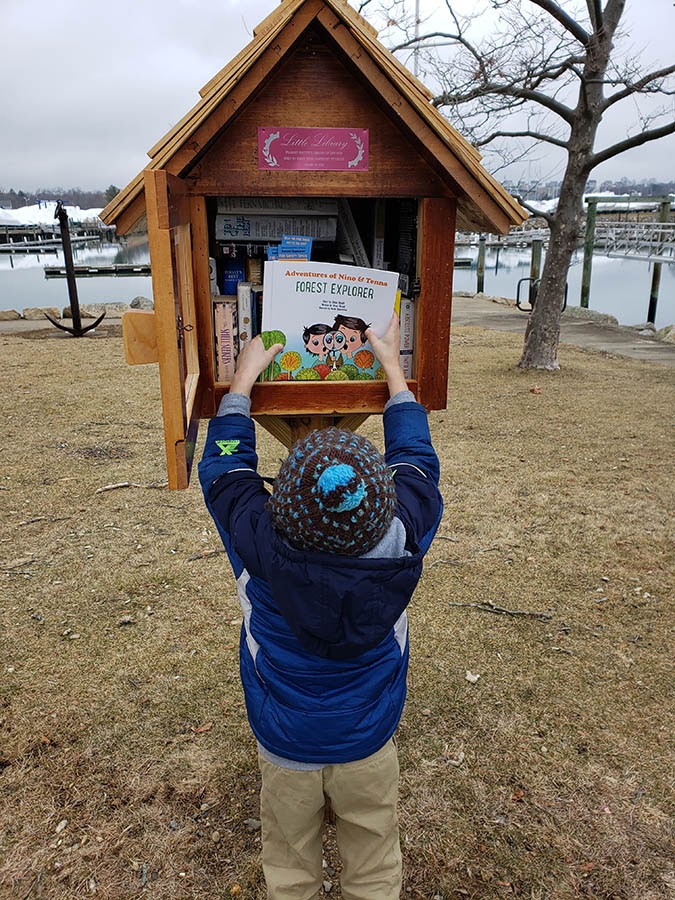 Ethan y su hijo dejando algunas copias de una historia en las cajas de Little Library en la ciudad