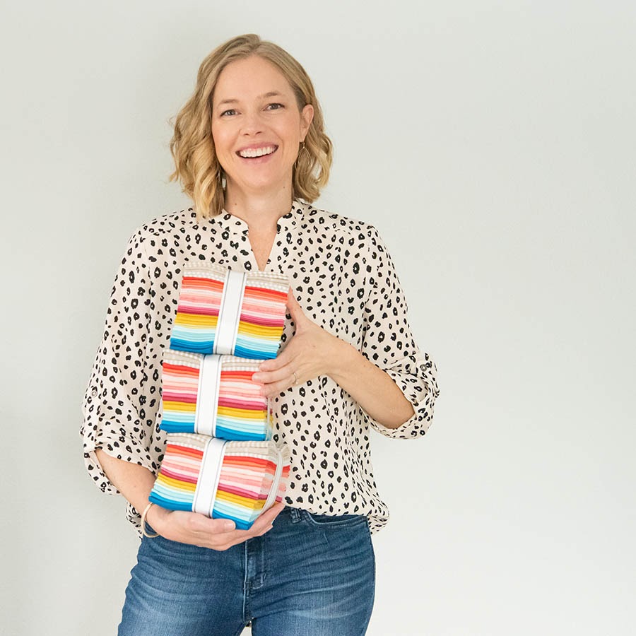 Quilty Love founder, Emily Dennis, holding quilt patterns.
