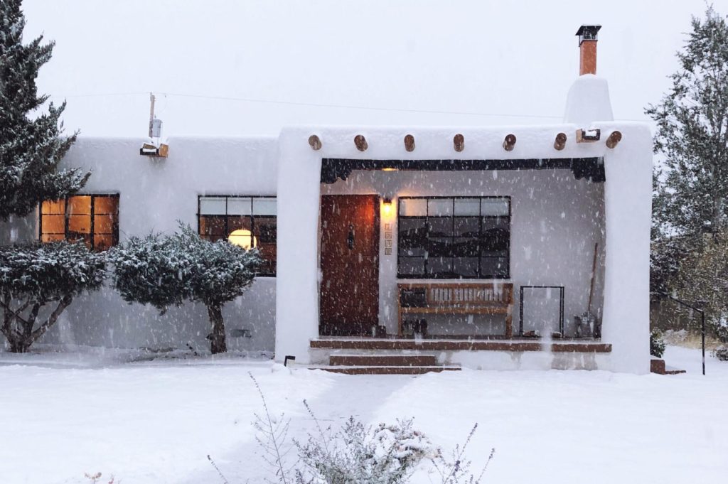 La casa de Anna Dorfman de mediados de siglo con estilo pueblo renacentista en Santa Fe, Nuevo México, cubierta en nieve